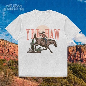 a white t - shirt with a cowboy riding a horse