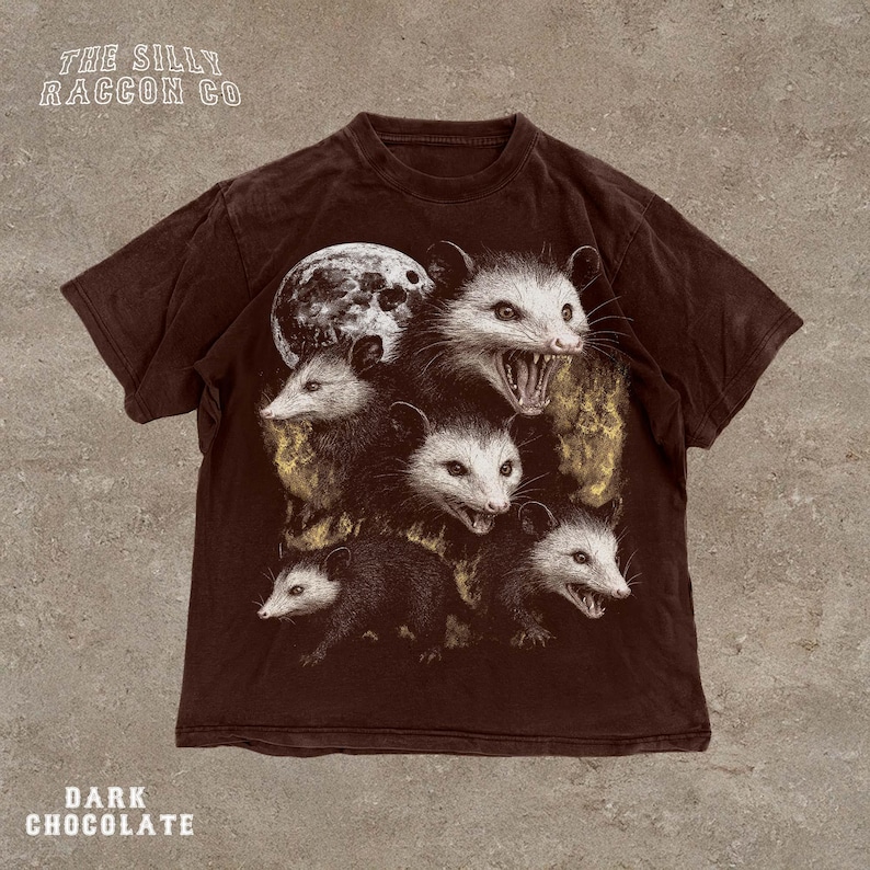 A dark brown t-shirt with a graphic design featuring multiple opossum faces with open mouths, creating a striking and visually captivating image.