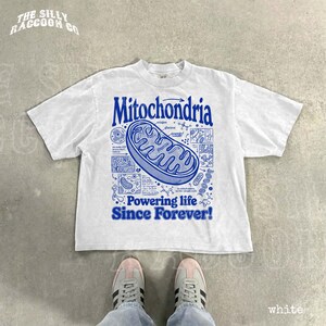 A white t-shirt with a graphic design featuring a Mitochondria-like structure and text, along with a pair of white sneakers.