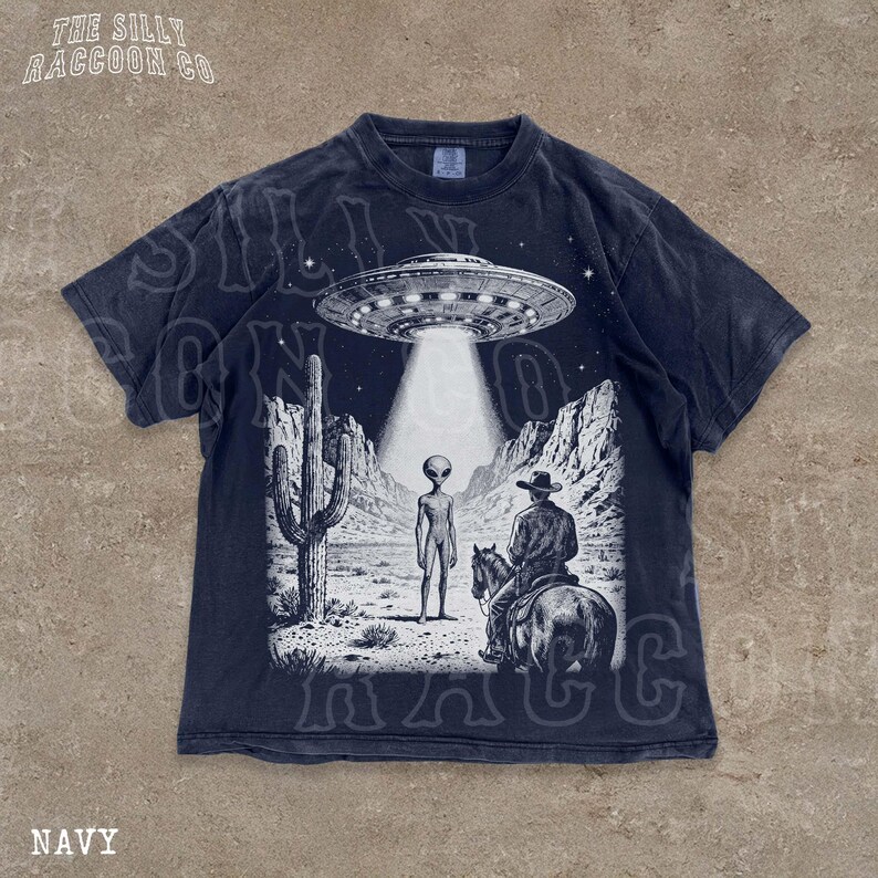 The image is a t-shirt design featuring a scene with an alien spacecraft hovering above a desert landscape, where a man on a horse is present.