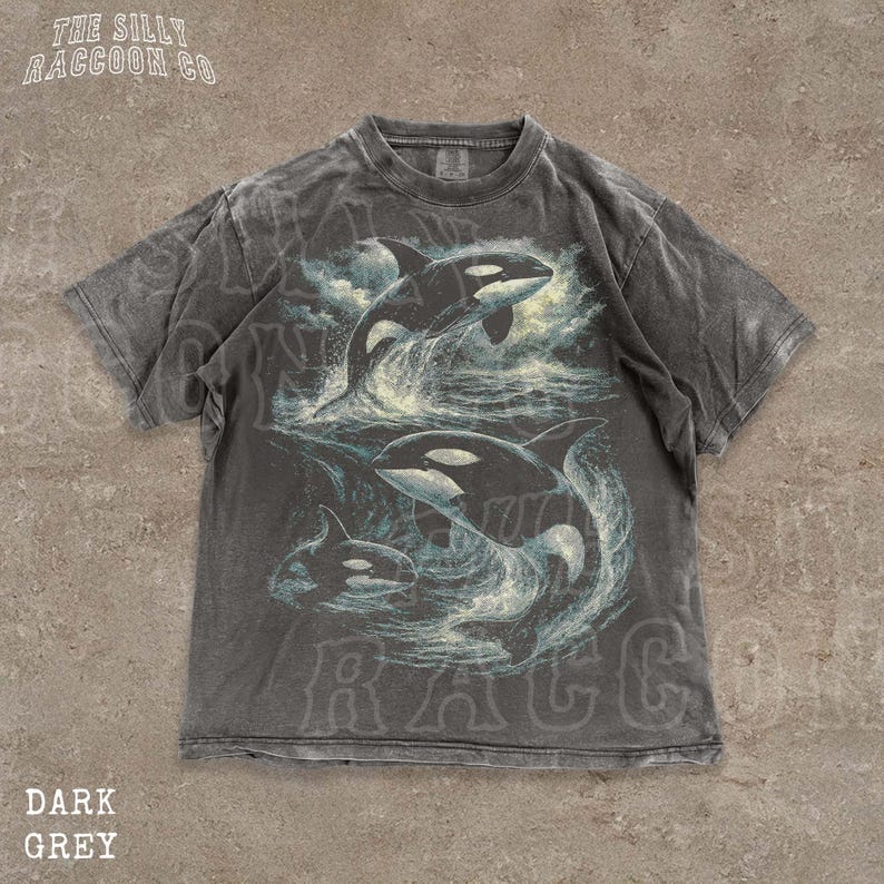 A gray t-shirt with a graphic design depicting two killer whales swimming in the ocean.