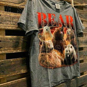 A grey t-shirt with a graphic design of a group of bears, with the word "BEAR" prominently displayed in red letters.