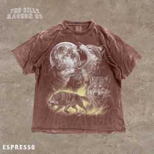 A t-shirt with a graphic design featuring a pack of wolves, including a howling wolf, a wolf with its mouth open, and a wolf walking through a field.