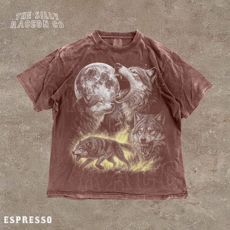 A t-shirt with a graphic design featuring a pack of wolves, including a howling wolf, a wolf with its mouth open, and a wolf walking through a field.