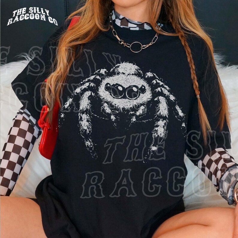 A person wearing a black t-shirt with a graphic of a spider printed on it.