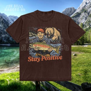 a brown shirt with a picture of a man holding a fish