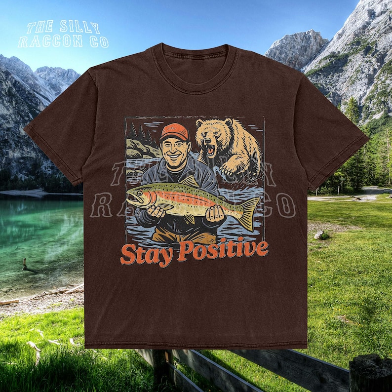 a brown shirt with a picture of a man holding a fish
