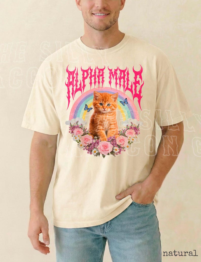 A man wearing a white t-shirt with a graphic design featuring a cat surrounded by flowers and a rainbow.