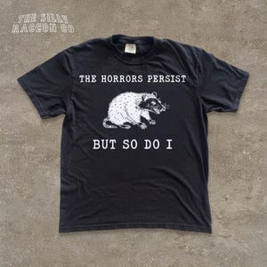 A black t-shirt with a graphic design and text printed on it.