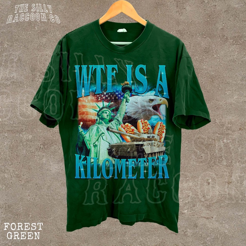 A green t-shirt with a graphic design featuring the Statue of Liberty and an eagle, along with the text "WTE IS A KILOMETER" printed on it.