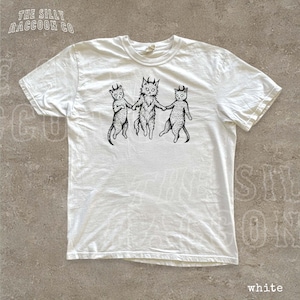 A white t-shirt with a black and white illustration of three cats holding hands.