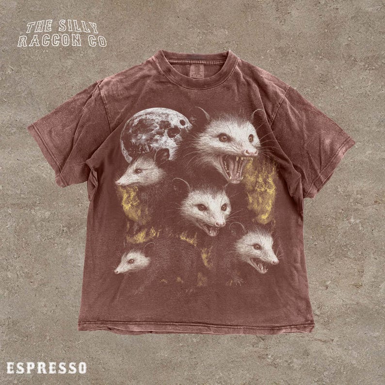 A t-shirt with a graphic design featuring multiple images of a cat's face, including one with a moon-like shape.