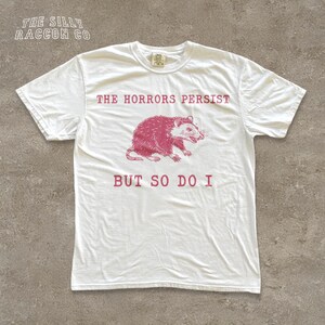 A white t-shirt with a graphic design and text printed on it.