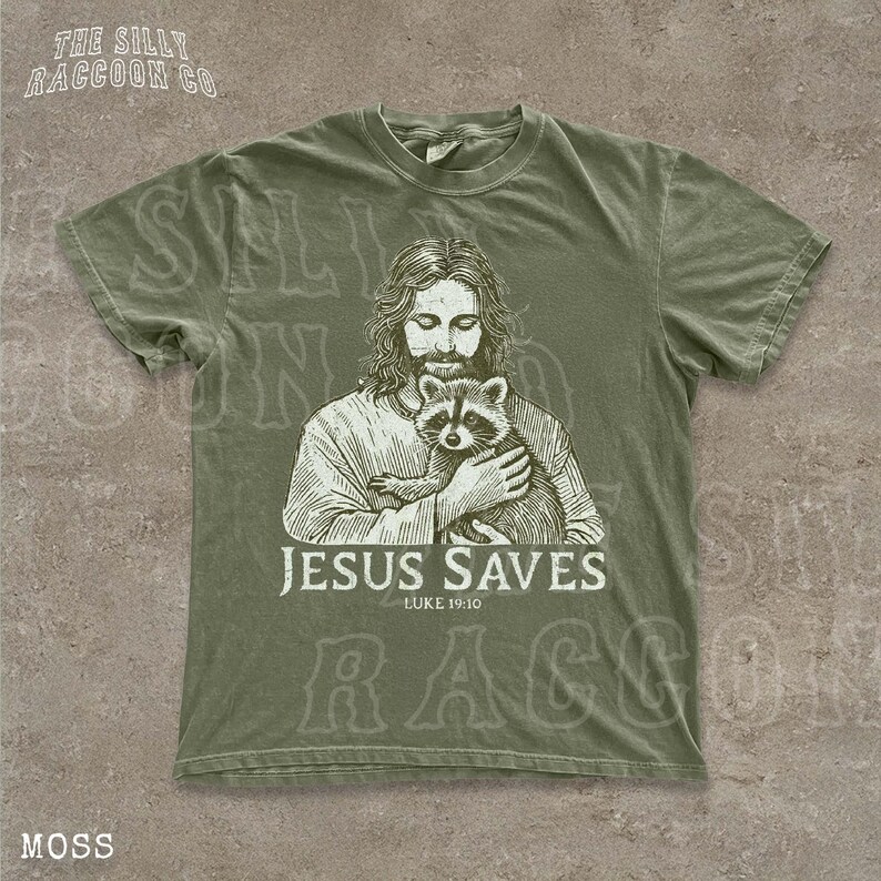 A t-shirt with a graphic design depicting a man holding a raccoon, along with the text "JESUS SAVES" and " Luke 19:10".