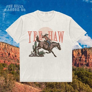 a white t - shirt with a cowboy riding a horse