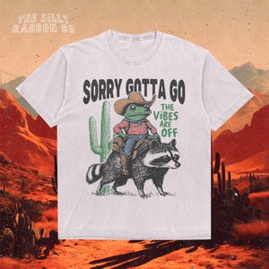 a white t - shirt with a picture of a man riding a racoon