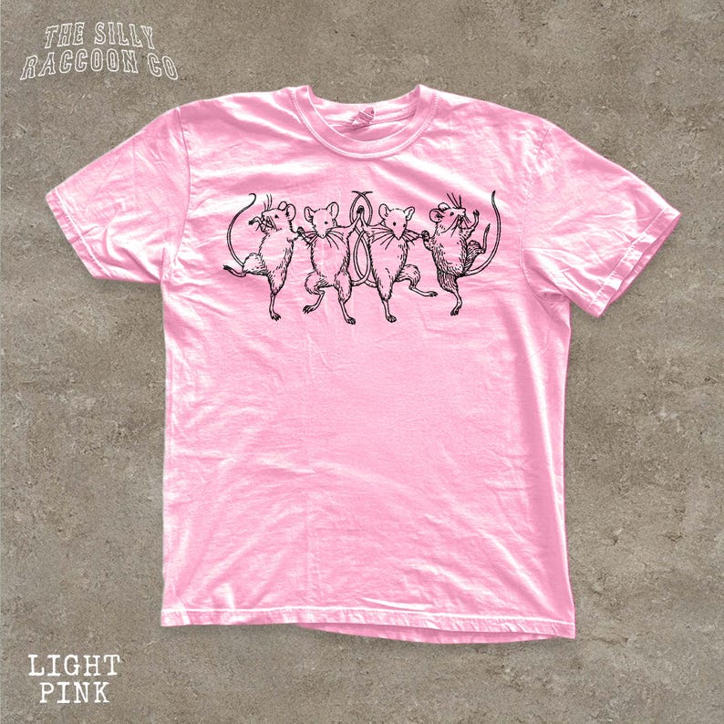 A pink t-shirt with a graphic design of five cartoon mice dancing together.