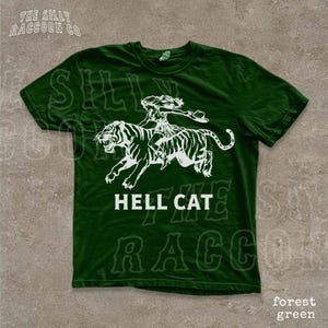 A green t-shirt with a white graphic design depicting a person riding a tiger.