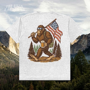 a t - shirt with a picture of a bigfoot holding a flag