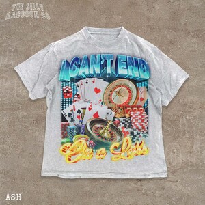 A white t-shirt with a graphic design featuring various casino-related elements, including playing cards, a roulette wheel, and stacks of chips. The text on the t-shirt reads "I CAN'T END" and "One Less".