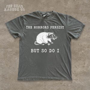 A gray t-shirt with a graphic design and text printed on it.