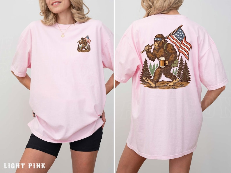 A woman wearing a pink t-shirt with an illustration of a Sasquatch carrying an American flag.
