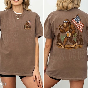 a woman wearing a brown t-shirt with an illustration of a giant gorilla holding an American flag and a mug.