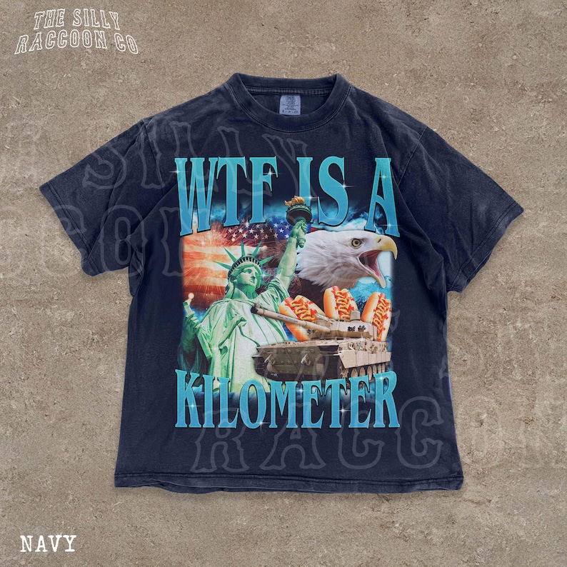 A navy blue t-shirt with a graphic design featuring the Statue of Liberty, an eagle, and hot dogs, along with the text "WTF IS A KILOMETER" and "NAVY".