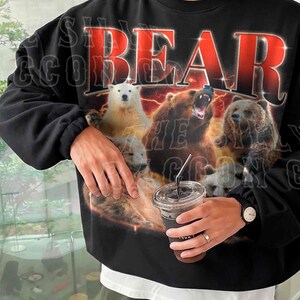 A person wearing a black sweatshirt with a graphic design featuring a polar bear and three other bears.