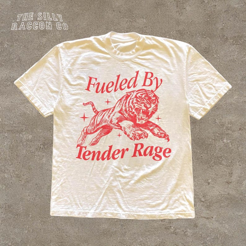 A white t-shirt with a red graphic design depicting a tiger and the text "Fuelled By Tender Rage" printed on it.