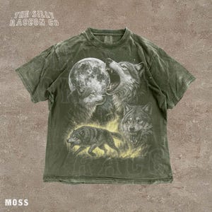A t-shirt with a graphic design depicting three wolves, one of which is howling at the moon.