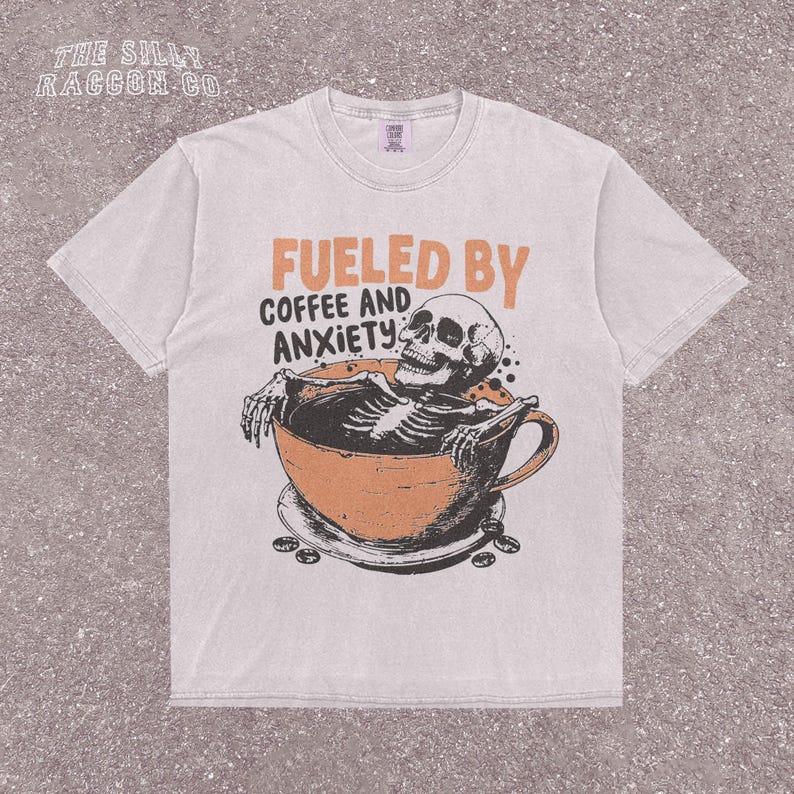 Funny coffee shirt for anxious introverts, featuring a skeleton relaxing in a giant coffee cup with the text “Fueled by Coffee and Anxiety.” Vintage grunge design with distressed print and muted tones. Ideal for women, men, and non-binary adults who love dark humor and caffeine culture. Great for Halloween, work-from-home vibes, mental health awareness, or gifting your favorite goth coffee lover.