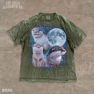 A t-shirt with a graphic design featuring three otters against a backdrop of a full moon and stars.