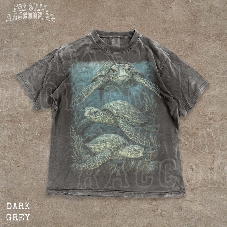 A t-shirt with a graphic design depicting three sea turtles swimming in the ocean.