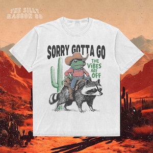 a white t - shirt with a picture of a man riding a racoon