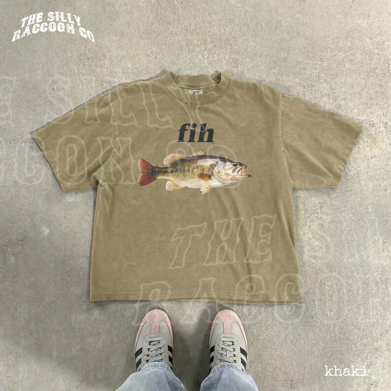 A pair of sneakers and a t-shirt with a fish graphic are shown on a concrete floor.