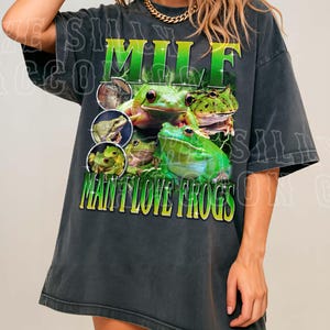A woman wearing a black t-shirt with a graphic design of green frogs.