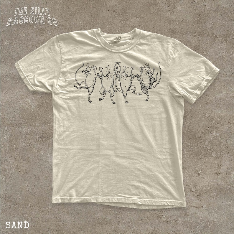 A white t-shirt with a graphic design of five mice dancing together.