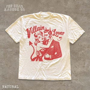 A white t-shirt with a graphic design featuring a man and a woman embracing, with the text " Villain Lover" above them.