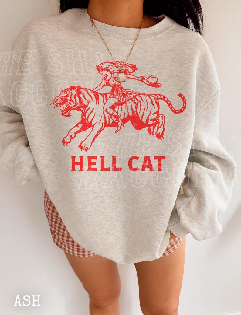 A person wearing a grey sweatshirt with a red graphic design depicting a person riding a tiger.