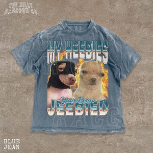 A t-shirt with a graphic design featuring two dogs, one black and one tan, with flames and text overlaying the image.