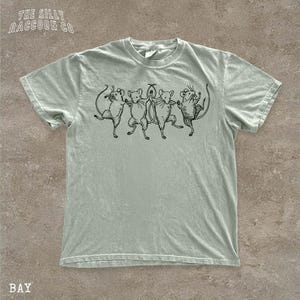 A light green t-shirt with a graphic design of five mice standing in a line, with one mouse slightly ahead of the others.