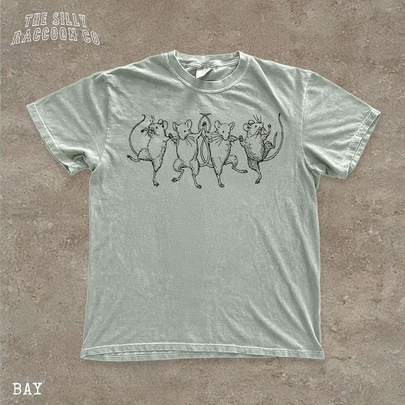 A light green t-shirt with a graphic design of five mice standing in a line, with one mouse slightly ahead of the others.