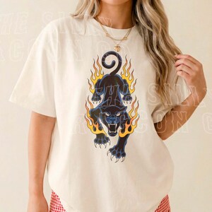 A woman wearing a white t-shirt with a graphic design of a black panther with flames on its back.