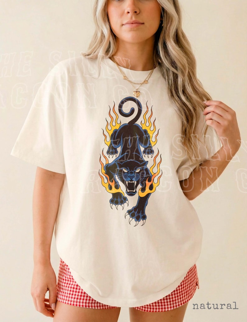 A woman wearing a white t-shirt with a graphic design of a black panther with flames on its back.