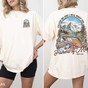 A woman wearing a white t-shirt with a graphic design on the back. The design features a mountain landscape with a fish and includes the text "Follow me and I will make you" and "Fishers of men" along with a Bible verse reference.
