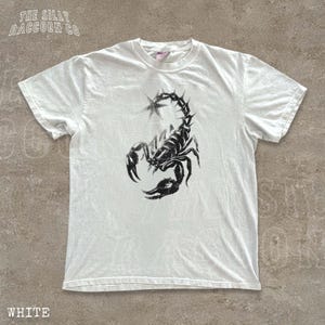A white t-shirt with a black graphic of a scorpion printed on it.