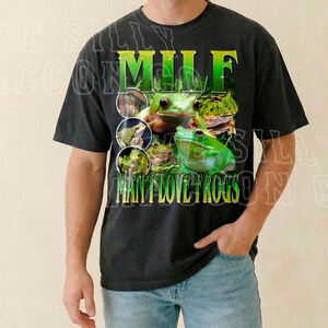 A man wearing a black t-shirt with a graphic design featuring a frog and the text "MILF MAN FLOYD ROGS" printed on it.