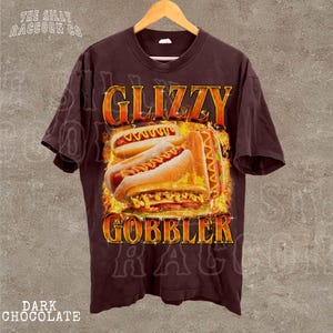 A dark brown t-shirt with a graphic design featuring a hot dog and the text "GLIZZY GOBBLER" prominently displayed.