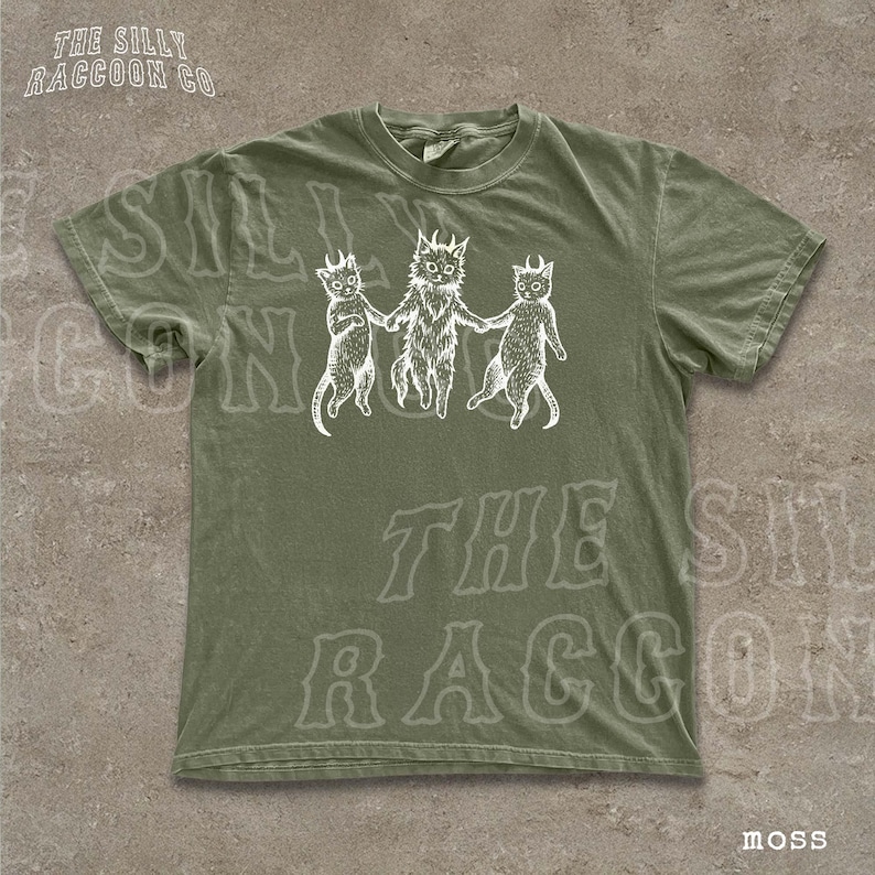 A green t-shirt with a graphic design featuring three cartoon cats holding hands.